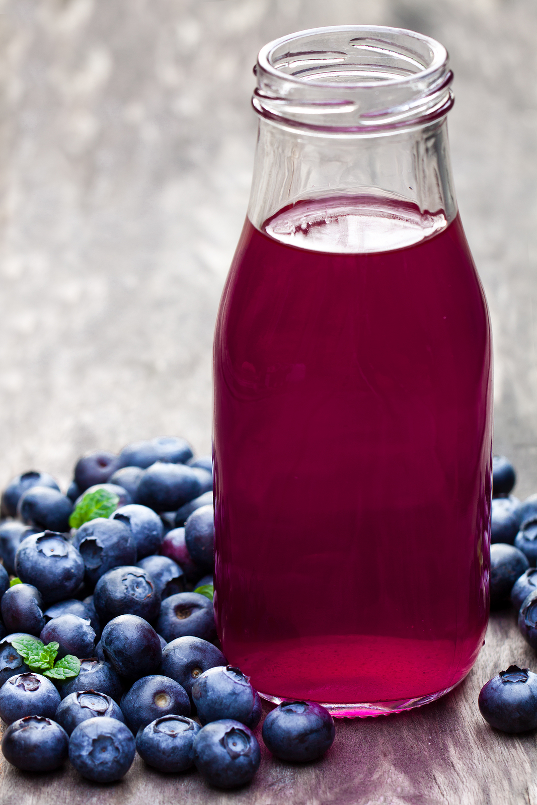 Blueberry juice in glass bottle on wooden table Amazing Wholeness LLC